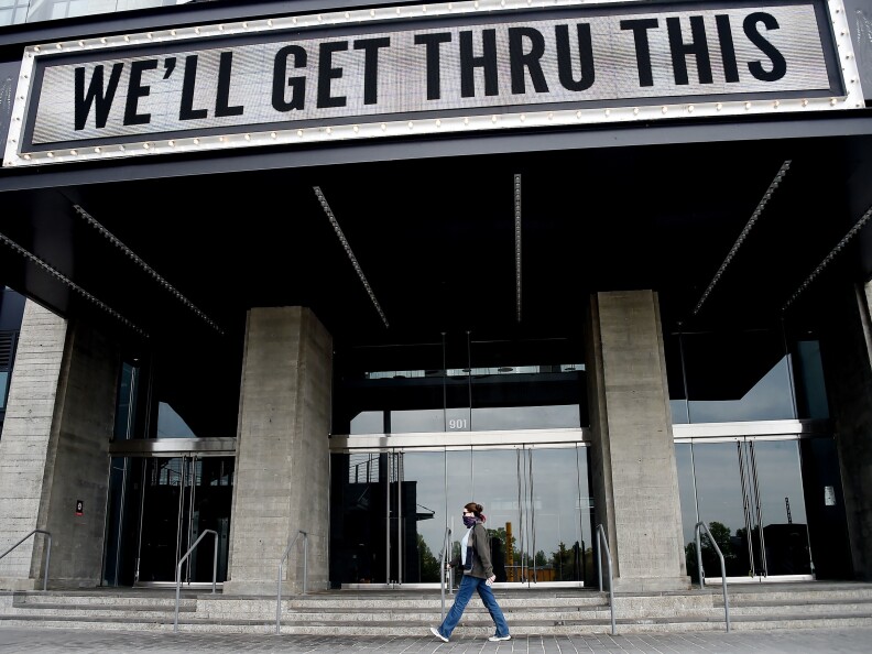 A person walks under a building sign that reads: "We'll get thru this."
