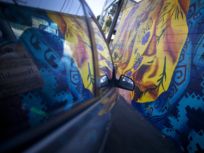 A car window reflects on of the pieces on Mural Mile along Van Nuys Boulevard in Pacoima.