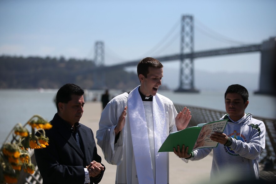 SAN FRANCISCO, CA - JULY 06:  Father Cameron Faller (C), associate pastor at the Church of the Epiphany, conducts a prayer service at the site where 32-year-old Kathryn Steinle was killed on July 6, 2015 in San Francisco, California. According to police, Steinle was shot and killed by Francisco Sanchez as she walked with her father on San Francisco's Pier 14 on July 1. Sanchez had been previously deported five times.  (Photo by Justin Sullivan/Getty Images)
