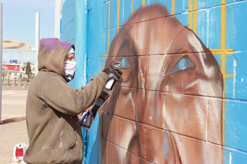 Gasak, a graffiti artist from South Africa, paints the face of Mother Teresa in a Juárez neighborhood.