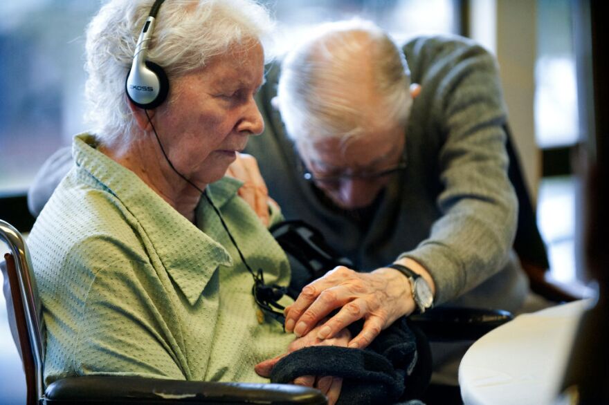 Frank M., 94, reaches for the hand of his wife of 68 years, Delores, 86, a resident with non-responsive dementia. While listening to music, Jessica Litchfield believes even the non-responsive patients have a "light in their eyes."