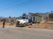A truck with a small home on it's trailer is parked in an empty lot