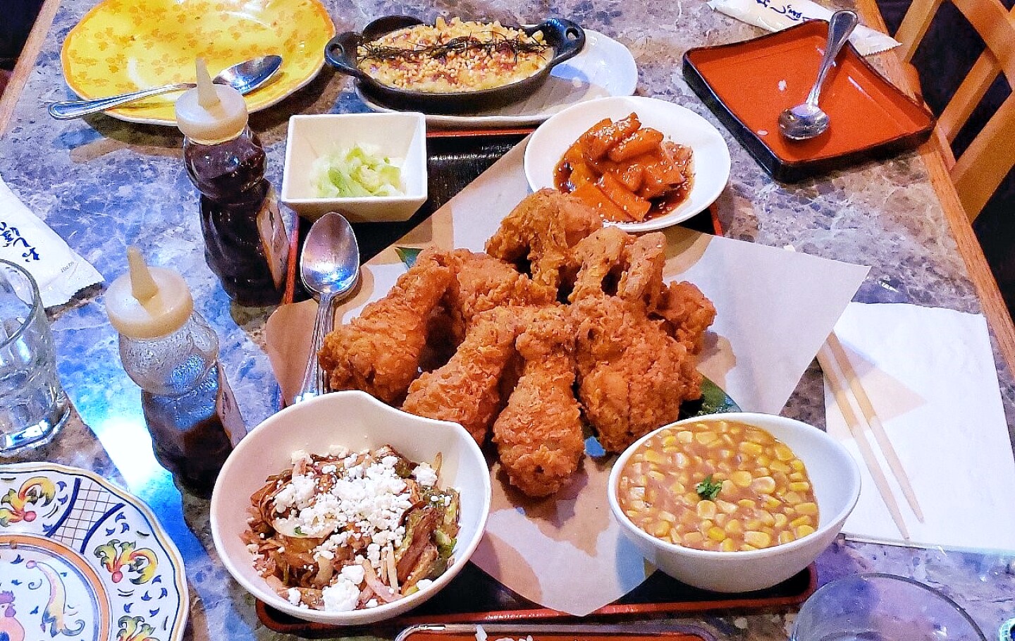 a plate of fried chicken surrounded by bowls of side dishes.