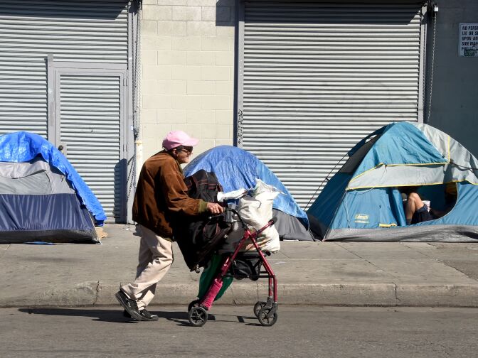 A woman pushes her walker past tents housing the homeless in Los Angeles, California on February 9, 2016.