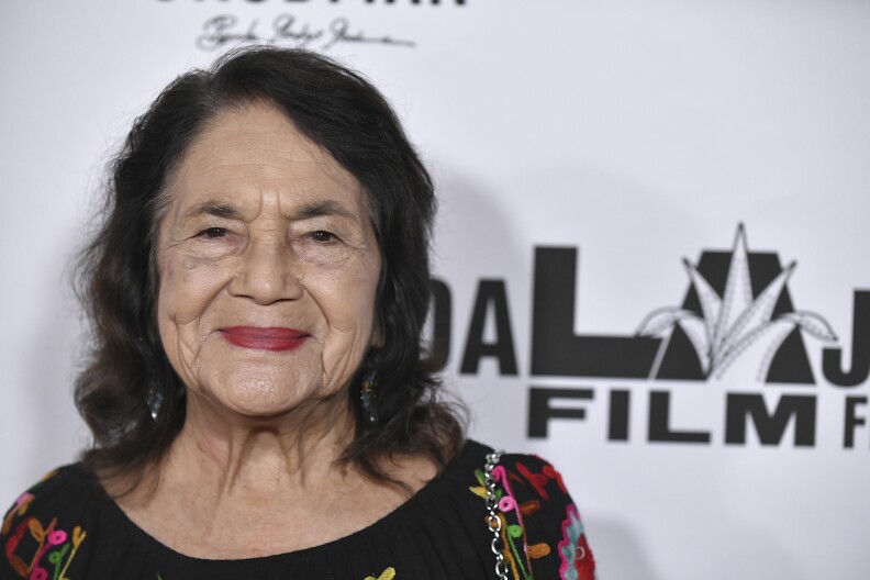 A close up of activist Dolores Huerta who wears a black top and florals during a setp-and-repeat for the GuadaLAjara Film Festival 2022.