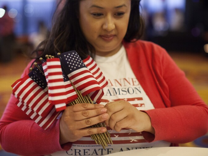 Cheryl Ocampo distributes flags on tables ahead of Marianne Williamson's election party at the Marriott in Marina del Rey.
