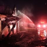 Firefighters hose down a burning house during the Tick Fire in Agua Dulce near Santa Clarita, California on October 25, 2019. - California firefighters battled through the night to contain a fast-moving wildfire driven by high winds that was threatening to engulf thousands of buildings. Around 40,000 people were told to flee the Tick Fire, which was raging across 4,000 acres (1,600 hectares) just north of Los Angeles. (Photo by Mark RALSTON / AFP) (Photo by MARK RALSTON/AFP via Getty Images)