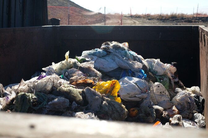 A dumpster full of bagged food waste