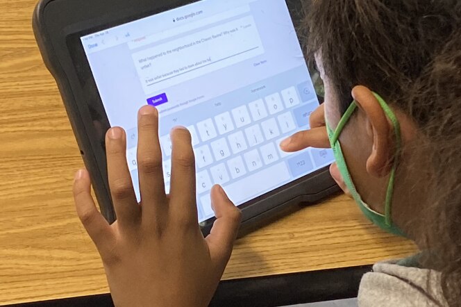 A sixth grader taps the screen of a tablet computer which is currently displaying a keyboard and a Google Form.