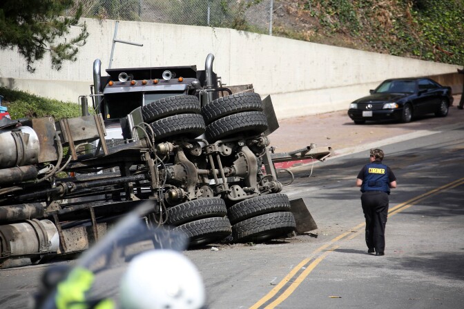 A Los Angeles Coroners official walks by the scene of a wreck Friday March 7, 2014 where a Los Angeles police officer was killed and another critically injured, when their cruiser was struck by a big rig at a Beverly Hills, Calif., intersection.  LAPD Officer Rosario Herrera says the collision occurred shortly before 8 a.m. Friday at Robert Lane and Loma Vista Drive, in a residential area of the city. (AP Photo/Nick Ut )