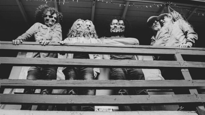 A black-and-white shot of four members of Orgōne the band standing on a balcony, double exposed.