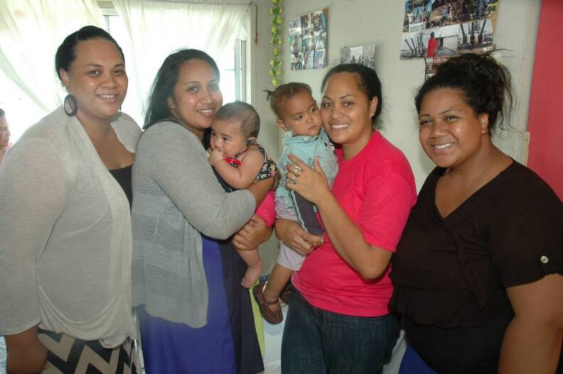 Four smiling Tongan American women. Two women in center are holding babies.