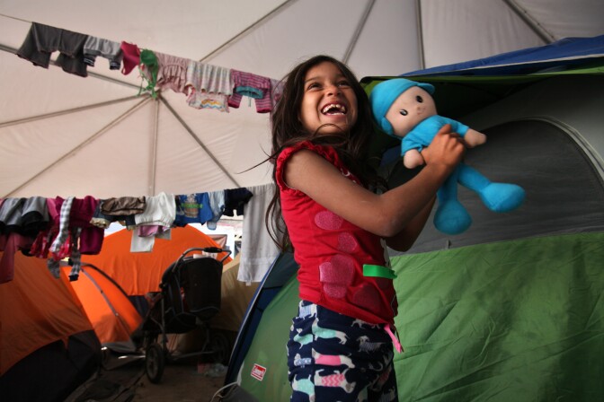 Tijuana, BAJA CALIFORNIA, Mexico - December 16, 2018.  At the El Barretal shelter in Matamoros, Tijuana, Ruth Reyes, 5, shows her mother a new doll she was given.

In Tijuana, Mexico, children members of the migrant caravan are learning to live in limbo as they move between shelters, settling in as much as possible to create a sense of normalcy, with help from NGOs, counselors and aid organizations. (Photo by Peggy Peattie)
