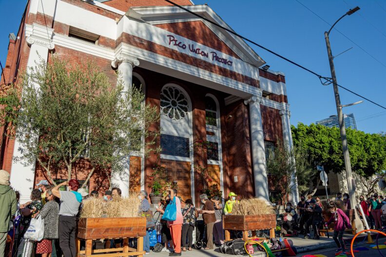 People are gathered outside of the Pico Union Project building for a festival.