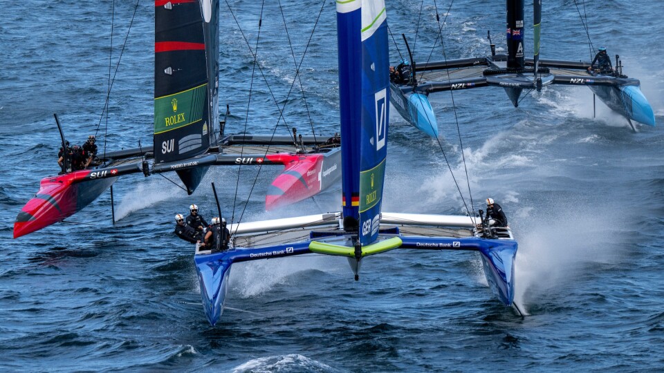 Three catamarans race in open water, each representing a different country: Switzerland, Germany and New Zealand. 