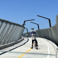 A cyclist in full gear taking a picture of the new bridge he is on.