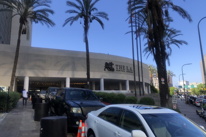 Cars parked in front of the L.A. Grand Hotel in downtown Los Angeles. Palm trees surround the hotel.