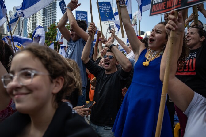 People cheer and smile along a city street.