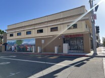A street corner with a shop closed up for the day with metal fencing protecting its windows. There are no people in sight.