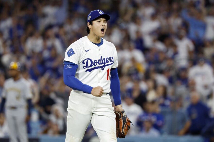 A man in a white Dodgers baseball uniform pumping his fist.