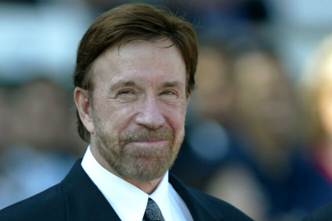 Chuck Norris wears a suit and tie. He has a beard.
