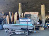 Pallets of wood, steel pipes and a sign that says "Westerbrook High" are piled at a set recycling company that operates under the 10 Freeway 