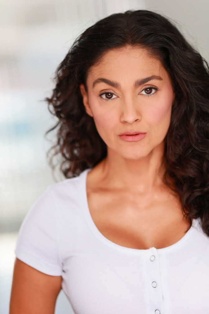Headshot of a curly-haired woman staring into the camera.
