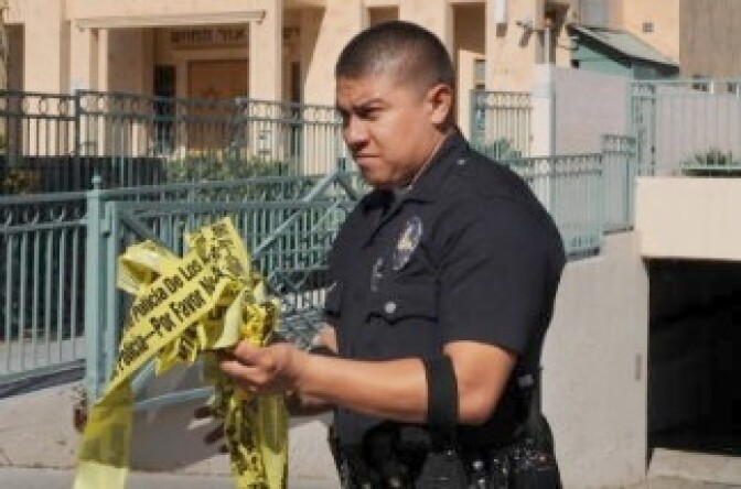 A policeman removes crime scene tape.