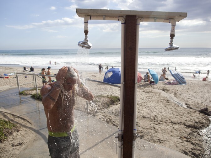 Matt Doll of Santa Cruz cools off under a shower at San Clemente beach. He was in town for the Hurley professional surfing competition. He was also happy to not have to wear a wetsuit in the water, he said.