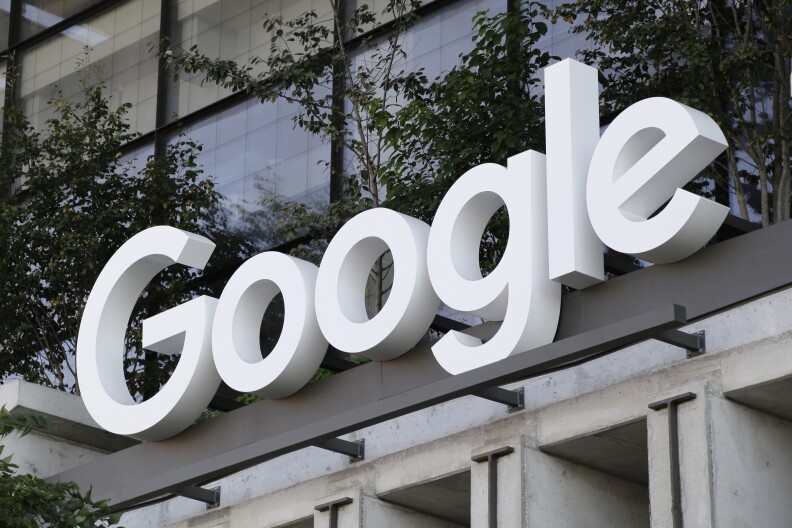 Large signage of the Google logo in white sitting over an entrance to a building with large windows.