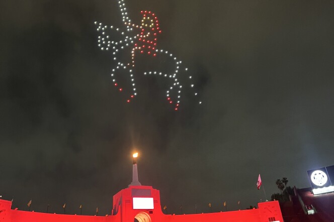 Lights in the night sky form a person on a horse carrying a sword wearing a gladiator outfit. Red lights light up the Coliseum. 