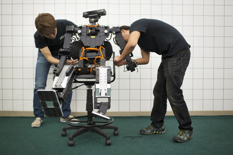Min Sung Ahn, left, who will be a mechanical engineering grad student in the fall, and Jeong Yoon, a first-year graduate student in mechanical design, are able to place THOR in a sitting position. To transport the robot to Pomona, THOR will hang inside a large wooden box.