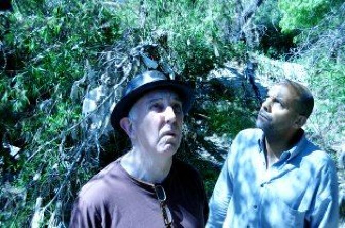 Lewis MacAdams of the Friends of the LA River and KPCC's Brian Watt survey some of the garbage in the bed of the LA River. Most of it comes storming through the stormdrains during the rainy season, and catches in the flora.