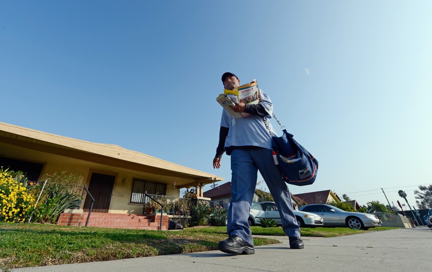 U.S. Postal Service employee Netza Suastegui delivers the mail on February 6, 2013 in Los Angeles, California. The U.S. Postal Service plans to end Saturday delivery of first-class mail by August, which could save the service $2 billion annually after losing nearly $16 billion last fiscal year.