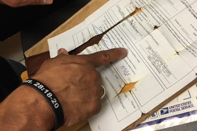Carlos Hidalgo points to an original document from his time in ICE detention that ended in 2015. He said he keeps the paperwork in his wallet as a reminder of his time at the privately-run facility in Adelanto, California.