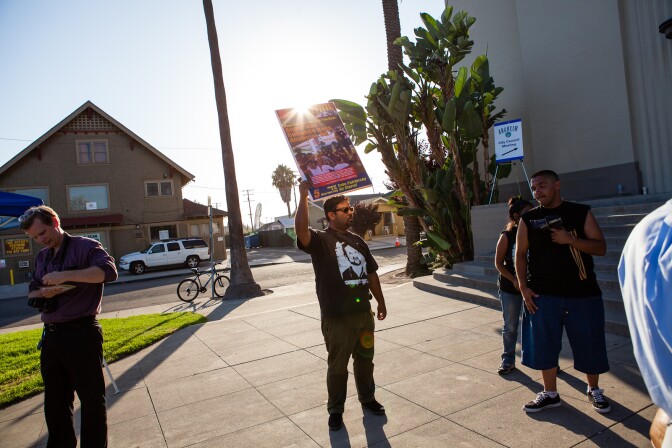 An activist holds a sign outside of Anaheim High School on August 8, 2012 during a special City Council meeting.