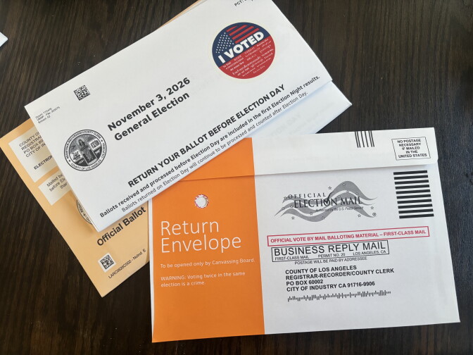 A Los Angeles County ballot envelope with an 'I Voted' sticker lies next to an orange return envelope for mail-in voting.