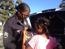 LAPD Sgt. Emada Tingirides hands out beaded bracelets and books to a girl in the Nickerson Gardens Housing Project in Watts. She coordinates the Community Safety Partnership program that focuses on building relationships in an area where distrust of the police runs deep.