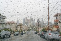 View of the downtown Los Angeles skyline from behind a rain-soaked car windshield.