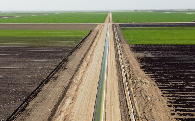 This aerial view shows an irrigation canal through agriculture fields.
