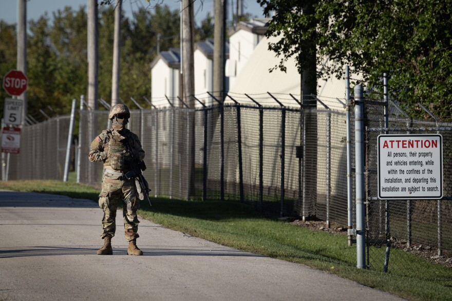 A man in a camouflage uniform stands guard.