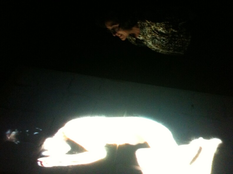 A docent looks at Sanja Ivekovic's video art at the Long Beach Museum of Art. It's an image of a woman sleeping projected onto a bed of dry ice. The image slowly disintegrates as the dry ice evaporates.