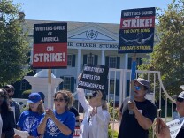 Striking writers and actors crowd the area outside Amazon Studios in Culver City. One person holds a sign that reads: Unemployment Benefits for Striking Workers. 