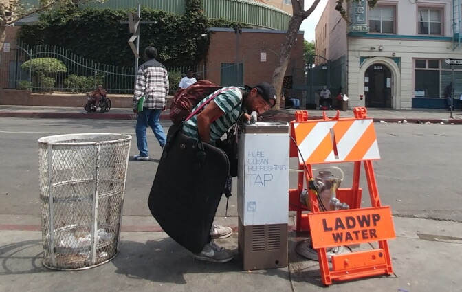 A resident of Skid Row takes a drink from one of the neighborhood's new drinking fountains. The fountains were installed to keep the area's homeless population hydrated during high temperatures. 