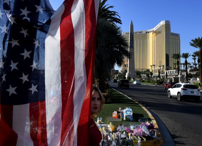 TOPSHOT - The US flag is left at a makeshift memorial outside the Route 91 music festival site beside the Mandalay Hotel October 4, 2017 on the Las Vegas Strip, after a gunman killed 58 people and wounded more than 500 others when he opened fire from the Mandalay Hotel on a country music festival in Las Vegas, Nevada. 
President Donald Trump heads to Las Vegas to meet mass shooting victims and first responders, as well as investigators who are hoping the girlfriend of gunman Stephen Paddock can help lift the mystery surrounding the weekend massacre. / AFP PHOTO / Mark RALSTON        (Photo credit should read MARK RALSTON/AFP/Getty Images)