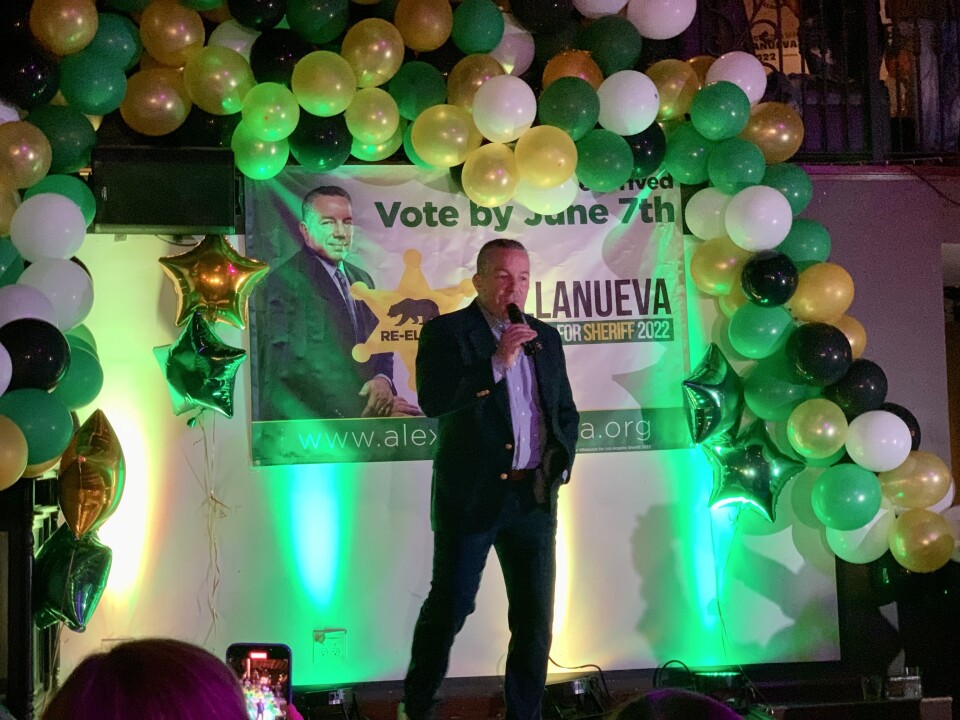 Villanueva stands on the stage with a mic in his hand. Baloons are around him.