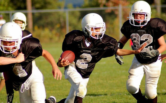 Group of youths participate in a game of tackle football.