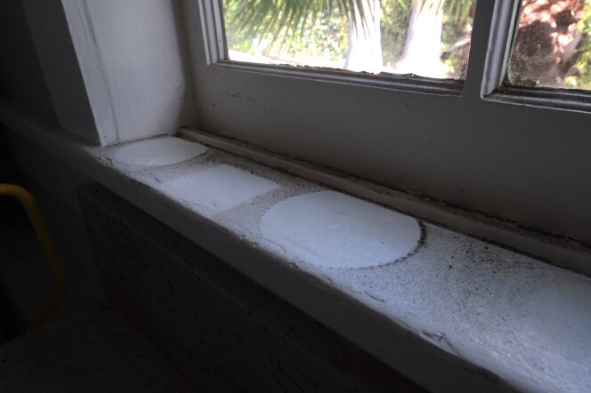A dark layer of ash from the Eaton Fire is visible on a windowsill that held potted plants. Health officials have said this ash potentially contains lead, asbestos and arsenic. 