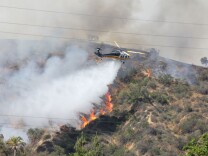 A Los Angeles County Fire Department helicopter drops water on a fire burning on the foothills of the San Gabriel Mountains in Monrovia, Calif., on Saturday, April 20, 2013. 