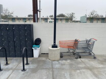 a wall of gray storage lockers, a bike rack, a lamp post and two shopping carts 